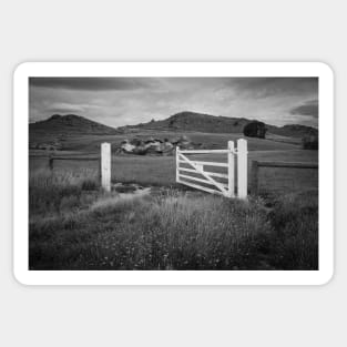 Open gate to field and distant hills with rock pile in monochrome. Sticker